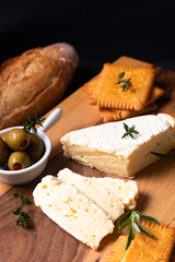 Food concept organic Brie cheese on wooden board on black slate stone with copy space