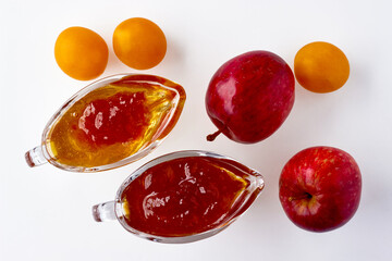 Red cherry plum apples and fruit jam in a glass gravy boat on a white background. Canned food