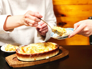 グラタンを小皿に取り分ける女性の手元