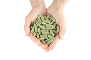 female hand holds green capsule superfoods moringa or spirulina 