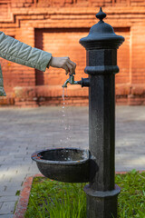 woman's hand opens the faucet of the water column on the street