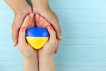 female hands hold a painted heart in the Ukrainian flag in male hands