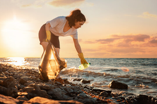 A Female Volunteer Is Collecting Plastic Garbage On The Seashore. Cleaning Of The Coastal Zone. Copy Space. The Concept Of Earth Day And Environmental Conservation