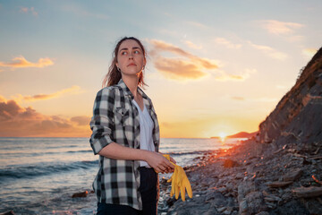 Portrait of woman holding rubber gloves. Copy space. Wild beach and sunset the background. The...