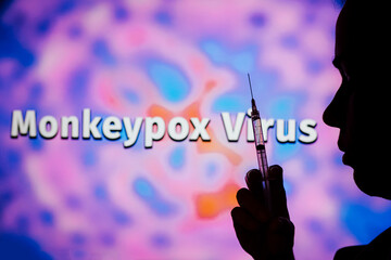 A person holding a medical syringe with the word Monkeypox in the background. It is a viral disease that occurs mainly in central and western Africa. It's called monkeypox. - obrazy, fototapety, plakaty