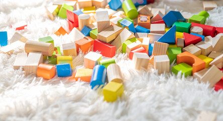 Toy colorful wooden blocks, multicolor bricks stack on a white fluffy rug. Educational logic games. Children's leisure