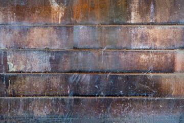 Rusted metal wall texture or old oxidized metal fence background with horizontal metal rusty tiles