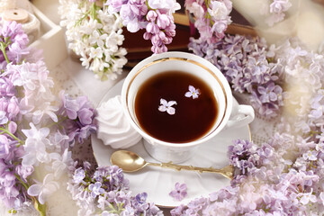 Top view of a cup of coffee in the middle of purple and white lilac blossoms