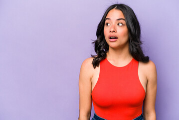 Young hispanic woman isolated on purple background being shocked because of something she has seen.