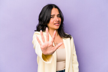 Young hispanic woman isolated on purple background rejecting someone showing a gesture of disgust.