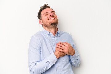 Young caucasian man isolated on white background has friendly expression, pressing palm to chest. Love concept.