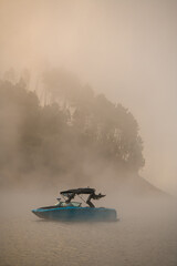 wonderful side view of bright motorboat on water covered with fog.