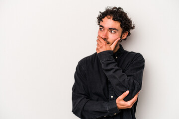 Young caucasian man isolated on white background thoughtful looking to a copy space covering mouth with hand.