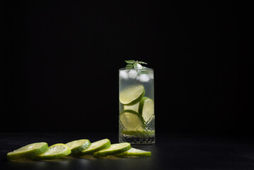 Un vaso de refrescante cóctel de jugo de lima con rodajas de lima y hielo sobre fondo negro  © R. Guas