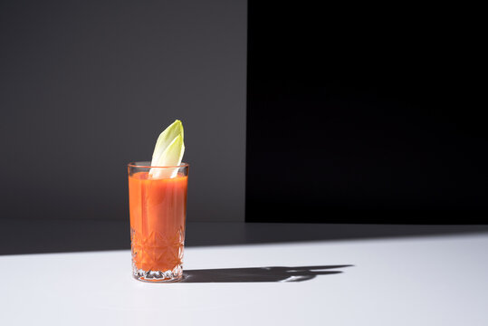 Vaso de jugo de zanahoria con hojas de endibia sobre fondo gris	