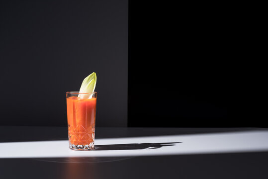 Vaso de jugo de zanahoria con hojas de endibia sobre fondo gris	