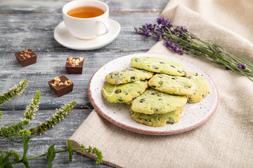 Green cookies with chocolate and mint with cup of green tea on gray wooden background. side view,...