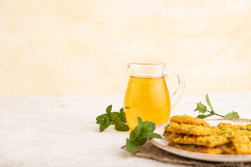 Traditional iranian dessert sohan with glass of green tea on a gray concrete background, side view,...