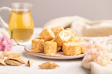 Traditional turkish delight (rahat lokum) with glass of green tea on a gray concrete background, side view, selective focus.