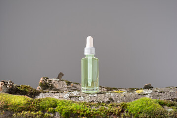 Botella de extracto de musgo, esencia con cuentagotas sobre un tronco de árbol con musgo. Producto...