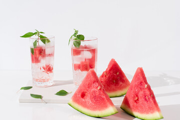 Dos vasos de zumo de sandía con trozos de sandia y hielo sobre fondo claro	