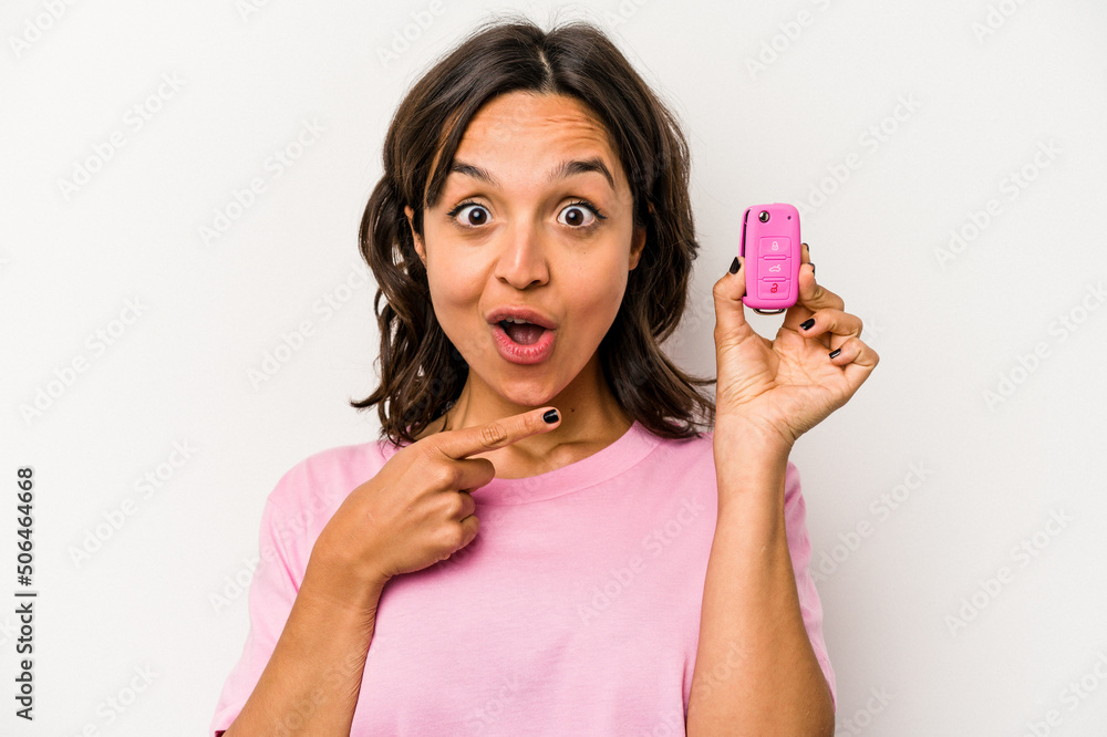 Wall mural Young hispanic woman holding car keys isolated on white background pointing to the side