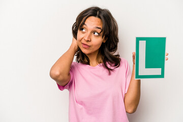 Young hispanic woman holding a beginner driver sign isolated on white background touching back of head, thinking and making a choice.