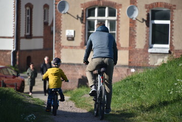 Ojciec i dziecko na rowerach na tle starej elewacji z antenami 