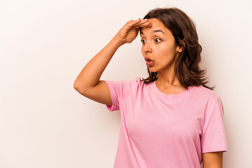Young hispanic woman isolated on white background looking far away keeping hand on forehead.