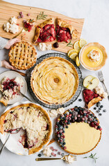 A thanksgiving feast of pie. Apple pie, berry pie, pecan pie, with two little hands holding onto a pie. 