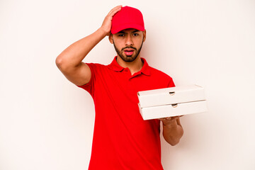 Young hispanic delivery man holding pizzas isolated on white background being shocked, she has remembered important meeting.