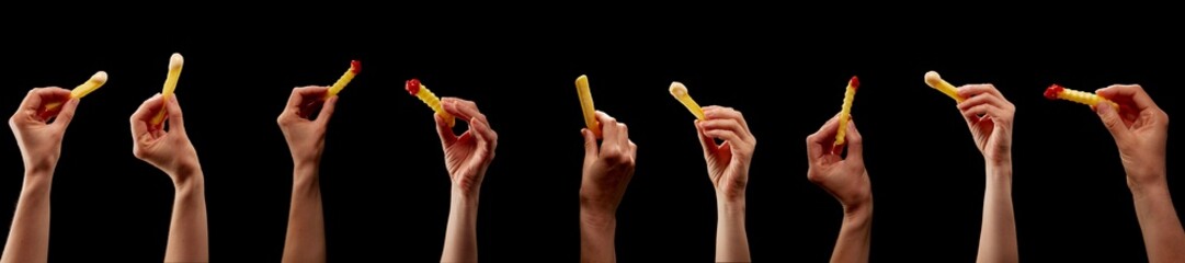 Some Hands with french fries in a row with mayonnaise and ketchup on black background - 506466424