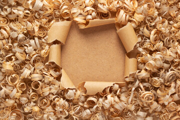 Wood shavings at torn paper background. Wooden shaving on cardboard texture