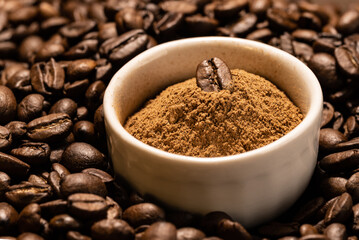 Finely ground cinnamon in a white ceramic bowl on a background of coffee beans