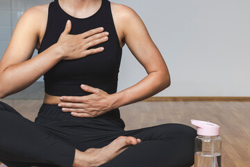 Woman doing breathing exercise sitting in lotus position. - obrazy, fototapety, plakaty