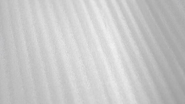 White striped thin protective foam plastic for package. Abstract background. Macro. Rotation