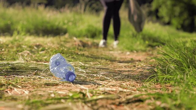Plogging. Person in sports clothes jogging at the forest and pick up garbage. The concept of volunteering and recycling.