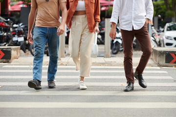 Cropped image of young people crossing road on pedestrian crossing in city