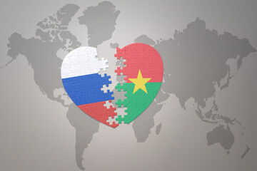 puzzle heart with the national flag of russia and burkina faso on a world map background. Concept.