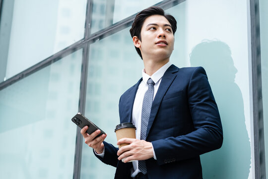 Image of Young asian businessman with glass building background