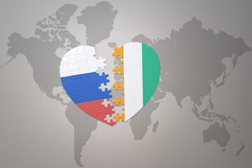 puzzle heart with the national flag of russia and cote divoire on a world map background. Concept.