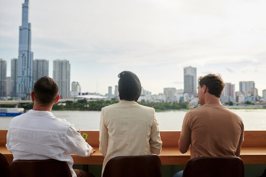 Young People Sitting At Rooftop Bar Counter, Drinking Cocktails And Enjoying Beautiful City View