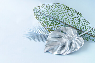 銀色のモンステラとヤシの葉と網目の葉のデザイン（造花・灰色の背景）