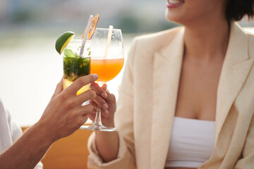 Closeup image of party guests toasting with glasses of sweet delicious cocktails