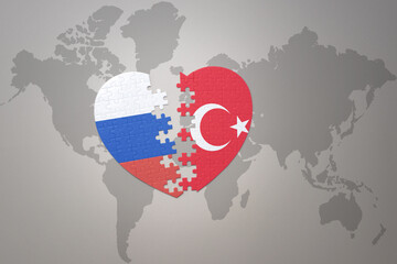 puzzle heart with the national flag of russia and turkey on a world map background. Concept.