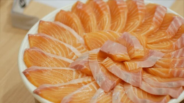 4k video of using chopctick pick slamon up from plate full of salmon sashimi, raw fish Japanese style food.