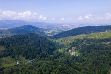 Mountains and forests in the vicinity of Bielsko-Biala. Sunny weather and green trees. The road in the middle of the forest.