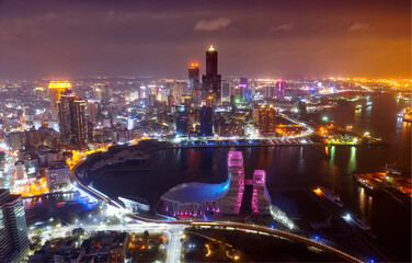 Fototapeta na wymiar Aerial skyline of Kaohsiung at night, a vibrant seaport in South Taiwan, with 85 Sky Tower amid skyscrapers, the futuristic architecture of Music Center next to the harbor & bridges across Love River