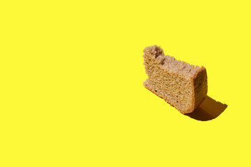 piece of black bread on a yellow background,  crust of bread, black bread with sliced slice