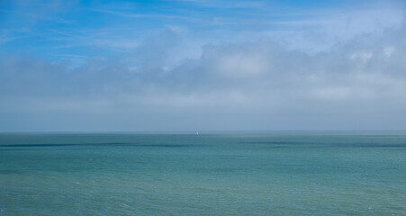 The sea with two distant yachts under a blue cloudy sky - obrazy, fototapety, plakaty